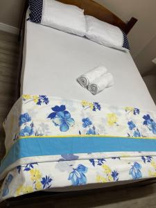 Una cama con colcha con flores azules. en A Jóia de Blumenau Home Office e Garagem Coberta, en Blumenau