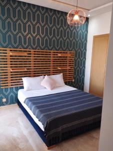 um quarto com uma cama grande e um cobertor azul em Casabay appartement pied dans l'eau 87 m2 em Sidi Rahal