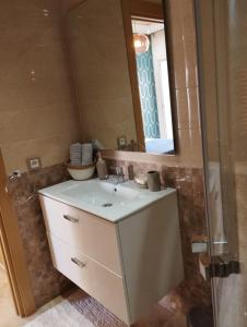 uma casa de banho com um lavatório branco e um espelho. em Casabay appartement pied dans l'eau 87 m2 em Sidi Rahal