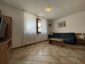 ein Wohnzimmer mit einem blauen Sofa und einem TV in der Unterkunft 078 Trilocale Baldino, Pinzolo in Pinzolo
