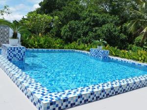 una piscina rodeada de azulejos azules y blancos. en Kapal Terbang Guest House Langkawi en Pantai Cenang