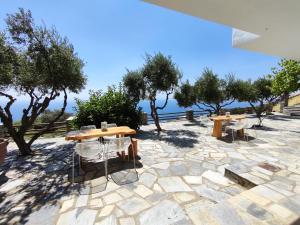 a patio with tables and chairs and trees at Alia's sea view villa & studios in Apróvaton