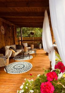 a porch with a couch and tables and flowers at Ranczo nad Cedronem in Kalwaria Zebrzydowska