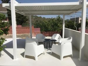 a patio with white chairs and a pergola at Campagne luxueuse de Sitges in Olivella