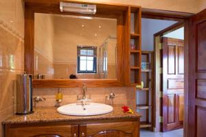 baño con lavabo y espejo grande en Belle Montagne Holiday Apartments en Grand'Anse