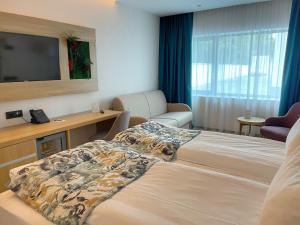 a hotel room with a bed and a flat screen tv at Alma Health & Spa Retreat in Brăila