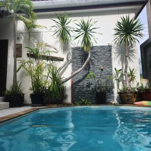a swimming pool in front of a house with palm trees at Bungalows Musch Kamala Phuket in Kamala Beach