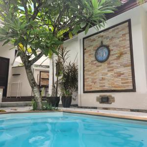 a large swimming pool with a clock on a wall at Bungalows Musch Kamala Phuket in Kamala Beach