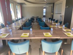 - une grande table avec des chaises bleues et des bouteilles d'eau dans l'établissement Logis Hôtel Le Bellevue, à Trévignin