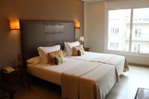 a bedroom with two beds and a large window at Hotel Ciudad de Vigo in Vigo