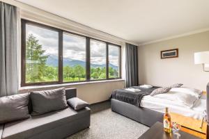 a bedroom with a bed and a couch and a large window at Hotel Helios in Zakopane