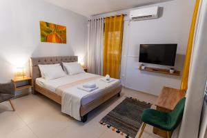 1 dormitorio con 1 cama, TV y silla en Lion's Cave suite No 1., en Kalamata