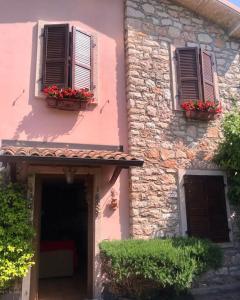a pink building with two windows and flowers on it at Villetta Indipendente in San Zeno di Montagna