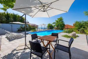 a patio with a table and chairs and an umbrella at Villa Oleander Apartman Aria in Poljane