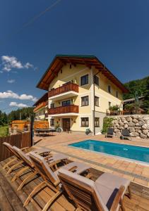 a house with a swimming pool and some chairs at Apparthaus Taxegger in Haus im Ennstal