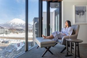 a woman sitting in a chair in front of a window at The Vale Niseko in Niseko