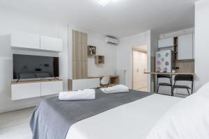 a white bedroom with a large bed and a kitchen at Santa Giulia Suite in Milan