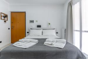 a white bedroom with a bed with towels on it at Santa Giulia Suite in Milan