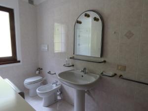 ein Badezimmer mit einem Waschbecken, einem WC und einem Spiegel in der Unterkunft Appartamento Panorama Lago di Ledro in Mezzolago