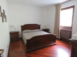 Schlafzimmer mit einem Bett, Holzböden und einem Fenster in der Unterkunft Appartamento Panorama Lago di Ledro in Mezzolago