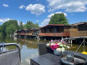 a house on the water with flowers on a table at Führerscheinfreies mobiles Hausboot in Rechlin