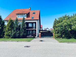 a house with a red roof on a street at Dom wczasowy Riviera in Ustronie Morskie
