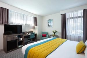 a hotel room with a bed and a desk and a television at Leonardo Hotel Brighton - Formerly Jurys Inn in Brighton & Hove