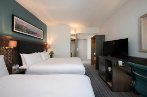 a hotel room with two beds and a flat screen tv at Leonardo Hotel Brighton - Formerly Jurys Inn in Brighton & Hove