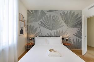 Riviera Flavour Apartments II by Wonderful Italy في سانتا مارغريتا ليغور: غرفة نوم بسرير أبيض وورق جدران استوائي