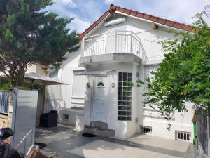 Casa blanca con balcón en la parte superior. en Charmante villa proche de la gare et de Paris, en Les Pavillons-sous-Bois