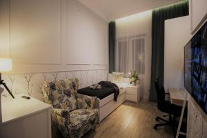 a bedroom with a bed and a chair and a tv at Elegancki apartament w centrum Warszawy in Warsaw