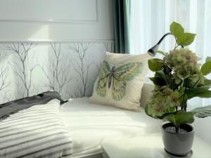 a bed with a butterfly pillow and a potted plant at Elegancki apartament w centrum Warszawy in Warsaw