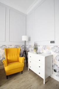a living room with a yellow chair and a dresser at Elegancki apartament w centrum Warszawy in Warsaw