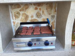 a grill with a bunch of hamburgers on it at Villa Sabine Apartment Brioni in Medveja