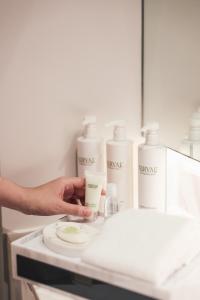 Una persona sostiene una botella de crema hidratante en un lavabo. en Courtyard by Marriott Bangkok Sukhumvit 20, en Bangkok
