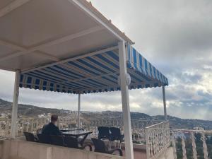 un hombre sentado bajo una pérgola en un techo en NOUARA Appart'hotel, en Chefchaouen