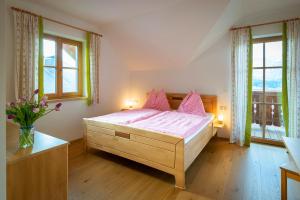 a bedroom with a bed with pink sheets and two windows at Haus Hödlmoser in St. Wolfgang