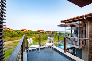 a balcony with two chairs and a view of the ocean at Oceans Edge 5, Zimbali Estate in Ballito