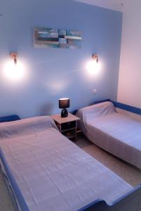 a bedroom with two beds and a table with a lamp at Aux portes de la Camargue in Jonquières-et-Saint-Vincent