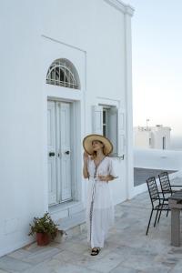 a woman wearing a hat standing next to a building at On An Island suites & apartments - Fira in Fira