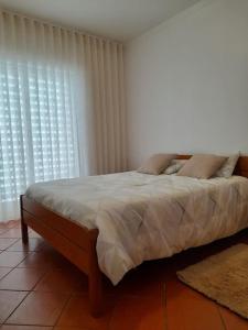 een slaapkamer met een bed met kussens voor een raam bij Casa das Mélias in Quarteira