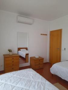 a bedroom with two beds and a dresser and a door at Casa das Mélias in Quarteira