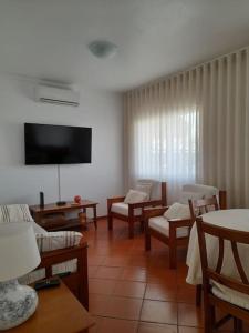 a living room with chairs and a flat screen tv at Casa das Mélias in Quarteira