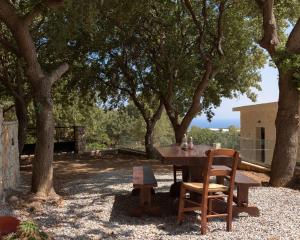 a wooden table and chairs sitting under trees at Mouria Country House in Gállos