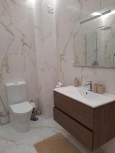 een badkamer met een toilet, een wastafel en een spiegel bij Casa das Mélias in Quarteira