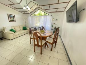 comedor con mesa, sillas y sofá en 3 Min from SJO airport Kaeli, en Alajuela