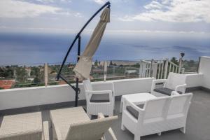 - Balcón con sillas blancas y sombrilla en Casa Merce en Arecida