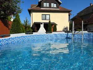 a large blue swimming pool in front of a house at A&A Apartmany in Liptovský Mikuláš