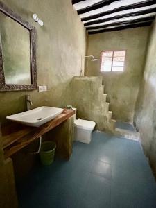 a bathroom with a sink and a toilet and stairs at Milele Lodge in Michamvi