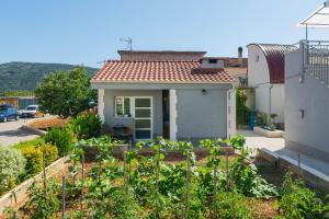 een klein huis met een tuin ervoor bij Studio apartman Mediteran in Marina